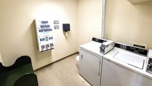 A laundry room with a wall-mounted soap and bleach dispenser, a dryer, and a washing machine.