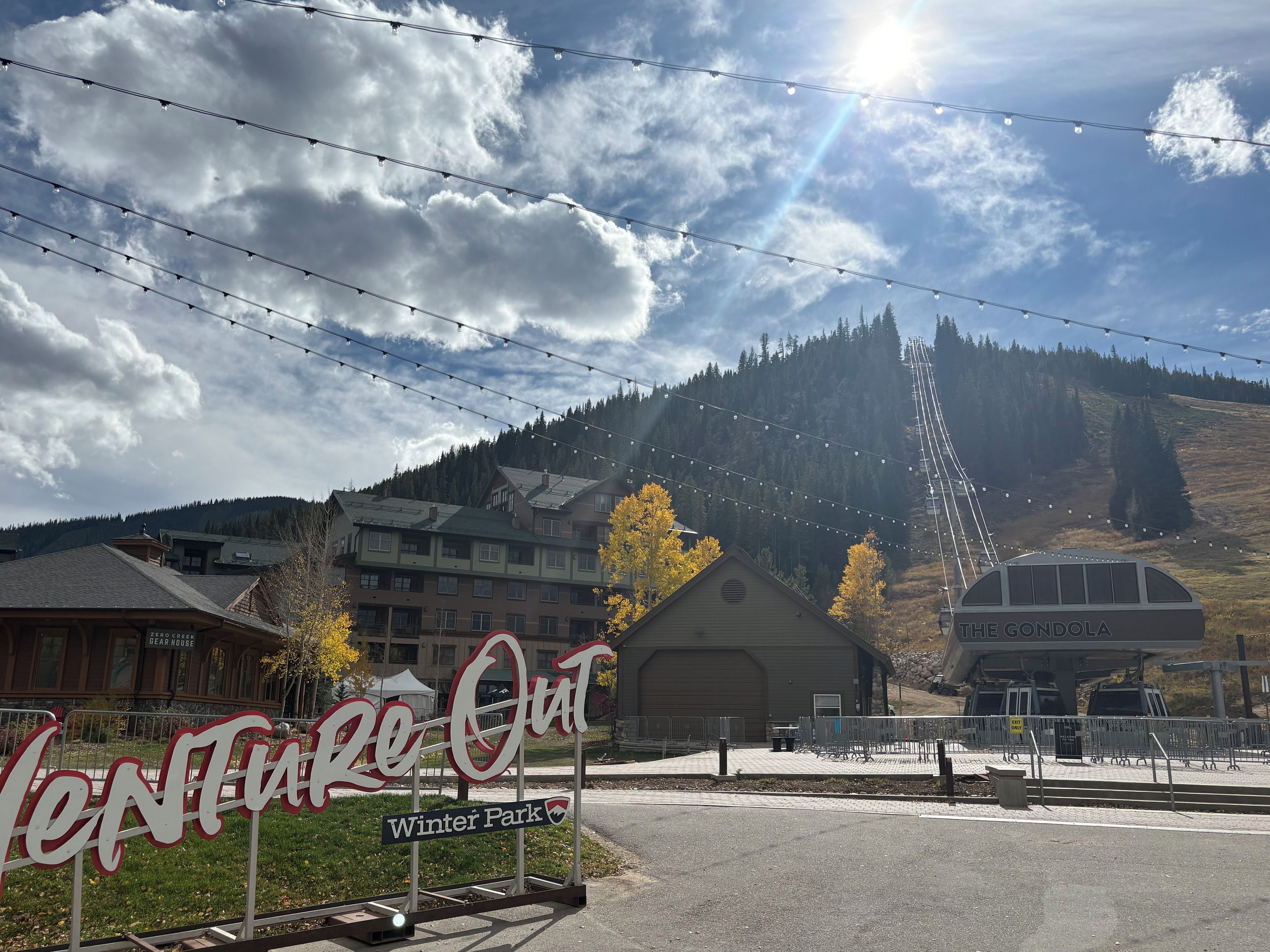 A sign for 'Venture Out Winter Park' with a view of a mountain and buildings in the background.