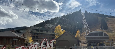 A sign for 'Venture Out Winter Park' with a view of a mountain and buildings in the background.