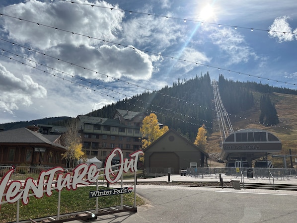 A sign for 'Venture Out Winter Park' with a view of a mountain and buildings in the background.