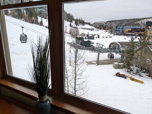 Blick auf einen Skigebiet mit Sessellift, Gebäuden und verschneiter Landschaft.