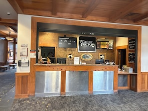 A reception desk at Winter Park Resort with a wooden interior, a digital display for current weather, and a sign welcoming guests.