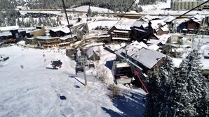 A ski resort with a chairlift, buildings, and snow-covered terrain.
