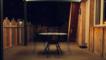 Un patio extérieur couvert avec une table et des chaises, une terrasse en bois et une vue sur le ciel nocturne.