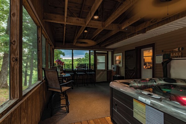 A wooden interior with a kitchen area, a dining table with chairs, and large windows offering a view of the outdoors.