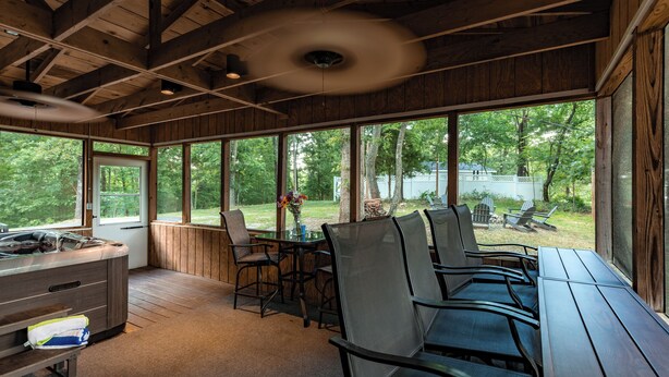 A covered outdoor area with a table and chairs, a bench, and a view of a wooded area. - Lakefront Home | Private Dock, Hot Tub & Kayaks (Murray)