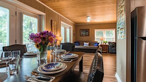 Un coin repas avec une table en bois dressée pour quatre personnes, entourée de chaises, et un vase de fleurs posé sur la table.