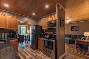A modern kitchen with wooden cabinets, stainless steel appliances, and a dining area with a view. - Lakefront Home | Private Dock, Hot Tub & Kayaks (Murray)