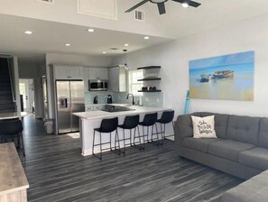 Relax in this open-plan living space with a central island, sofa, and staircase leading to another level.