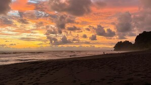 A beach with a sunset and clouds. - Cabinas Brisa Del Mar (Jacó)