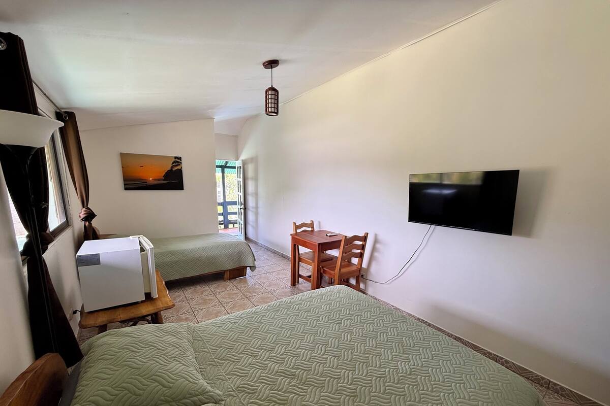 A room with two beds, a TV, a table, and a painting on the wall.