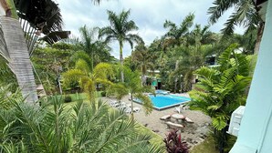 A pool area surrounded by lush greenery, including palm trees and various plants. - Cabinas Brisa Del Mar (Jacó)