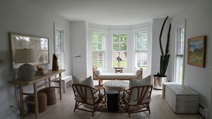 Un salón luminoso y espacioso con ventanal, muebles de madera y vistas al jardín trasero.