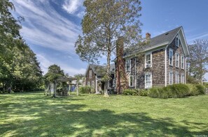 A large, two-story wooden house with a well-maintained lawn and a gazebo.