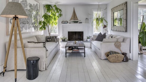 Una sala de estar con chimenea blanca, dos sofás, una mesa de centro y una lámpara.