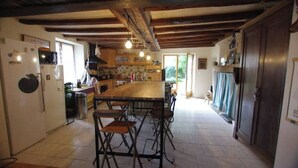 Una cocina rústica con una isla de madera, taburetes de bar y un respaldo de piedra.