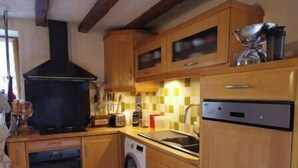 Una cocina compacta con armarios de madera, horno empotrado, lavadora y estufa.