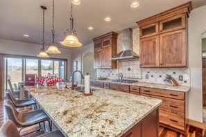 A kitchen with a large island, wooden cabinets, and a view of the outdoors. - Mimosa Fields: Designer Kitchen w/ Outdoor Oasis (Fruita)