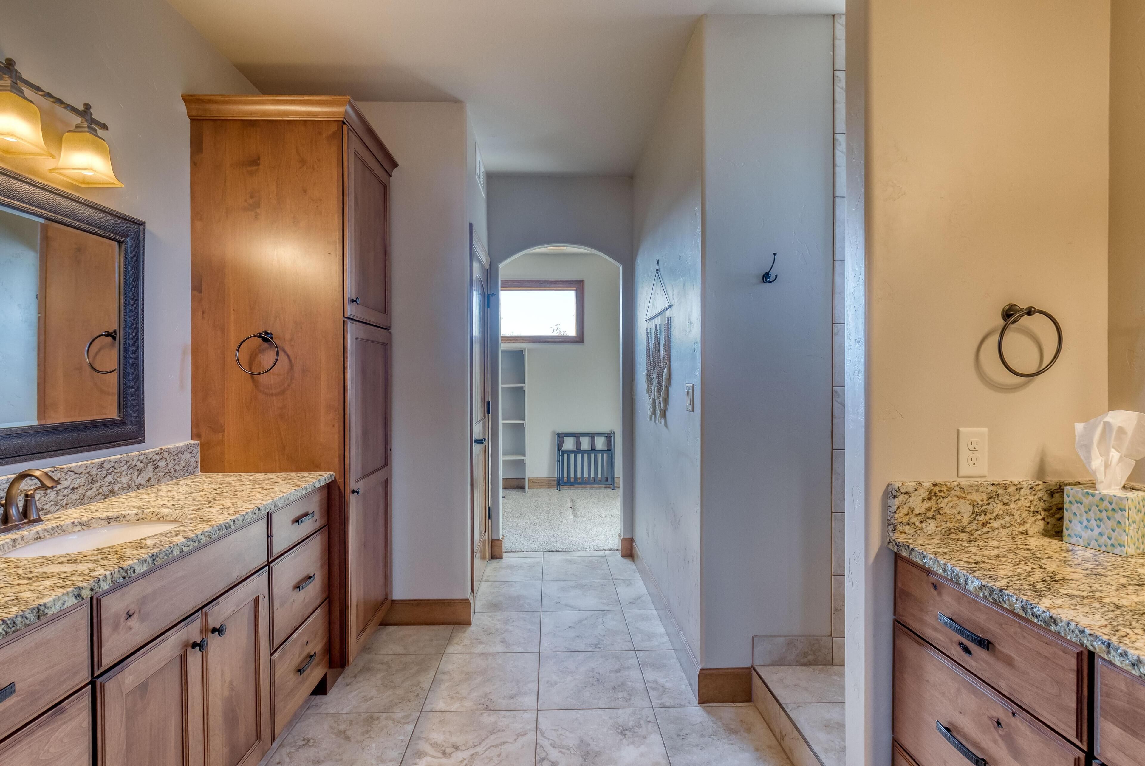 A bathroom with wooden cabinets, granite countertops, and a large mirror.