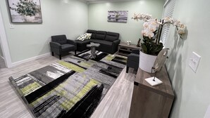 Uma sala de estar moderna com um sofá seccional, duas poltronas, uma mesa de centro e um tapete decorativo.