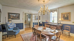 Ein Esszimmer mit einer Chandelier, einem Holzessttisch, Stühlen und einem blauen Sessel.