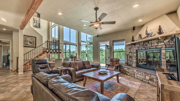 A spacious living room with a leather sectional sofa, a fireplace, and a stone accent wall. - Scenic Ruidoso Home w/ Large Deck + Hot Tub! (Ruidoso)