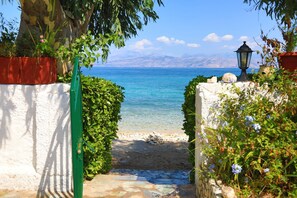 A stone pathway leading to a beach with a clear view of the sea and distant mountains. - Beach Villa Varvara (Corfu)
