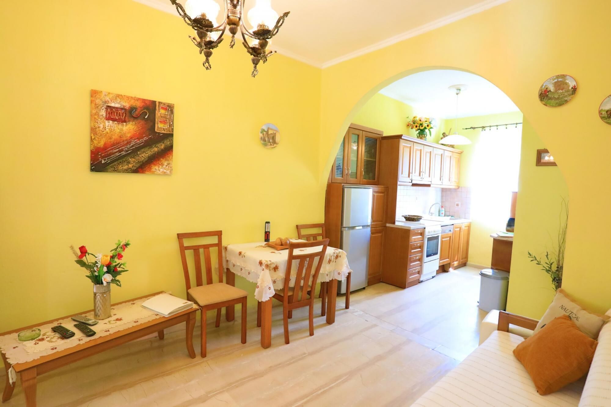 Un coin repas avec une table dressée pour deux personnes, un lustre et un tableau accroché au mur.