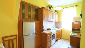 Une cuisine de taille réduite, dotée de meubles de rangement en bois, d’un réfrigérateur, d’un évier et d’une cuisinière.