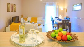 A dining area with a table set for two, a bottle of wine, and a fruit basket. - Villa Valentina in Corfu (Corfu)