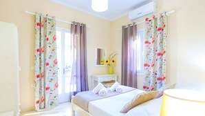 A hotel room with a bed, curtains, a bedside table with a vase of sunflowers, and a lamp. - Villa Valentina in Corfu (Corfu)