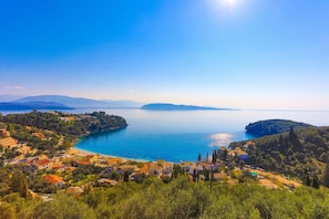 A coastal town with a clear view of the sea and mountains in the background. - The Old Office in Kalami (Corfu)