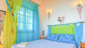 A bedroom with a bed, curtains, a bedside table, and wall decorations. - The Old Office in Kalami (Corfu)