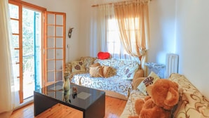A cozy living room with a sofa, a coffee table, and a teddy bear. - The Old Office in Kalami (Corfu)