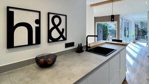 Een moderne keuken met een centraal eiland, inbouwspots en grote zwart-wit kunst aan de muur.