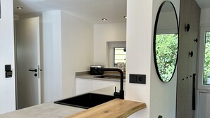 Een moderne keuken met een houten aanrecht, een zwarte barkruk en een grote spiegel.