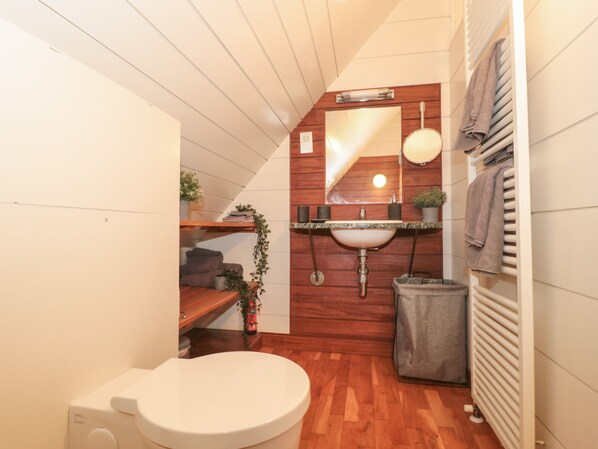 A compact bathroom with a white toilet, wooden vanity, and a small sink.