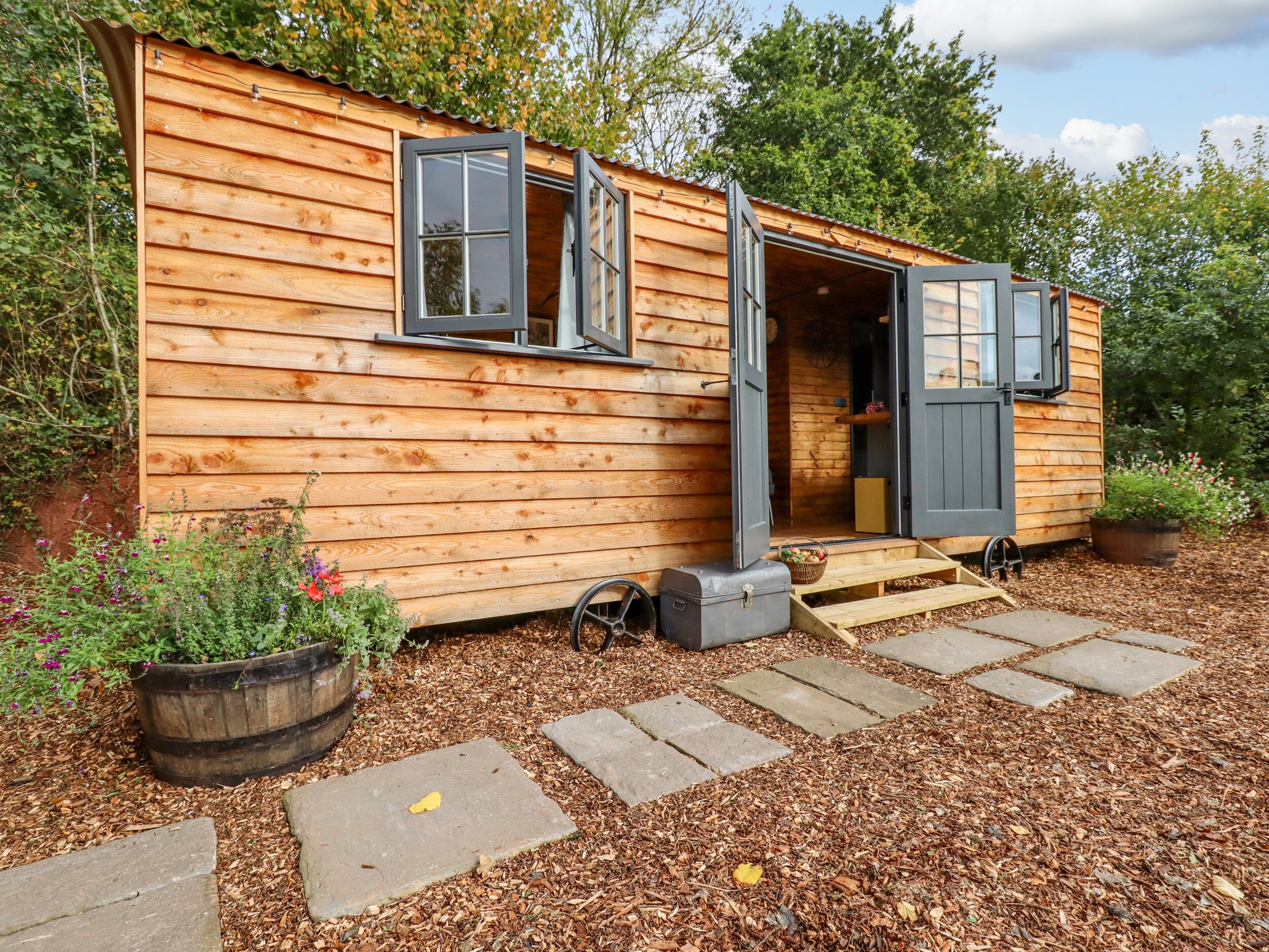 A wooden cabin with a large open door, a window, and a small porch area.