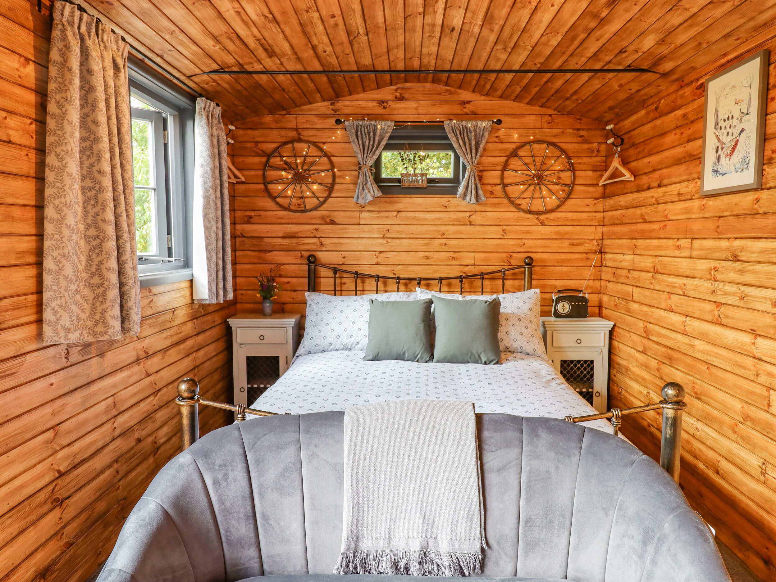 Een gezellig houten blokhut slaapkamer met een bed, nachtkastjes en een raam met gordijnen.