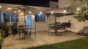 Eine Außenpatio mit Tischen, Stühlen, Lichterketten und Sonnenschirmen.