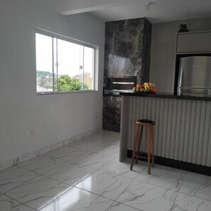 Uma cozinha moderna com uma janela grande, forno embutido e geladeira de aço inoxidável.