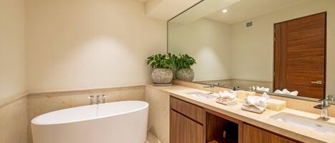 A modern bathroom with a freestanding bathtub, a large mirror, and wooden cabinetry.
