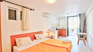 Una camera d'albergo con due letti, angolo cottura, bagno e balcone.