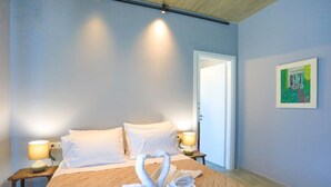 A hotel room with a bed, two bedside lamps, a door, and a painting on the wall. - Villa Christina in Poulades (Corfu)