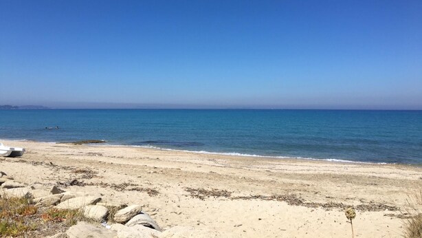 A sandy beach with a clear blue sky and calm sea. - Amarylis Apartment in Corfu (Corfu)