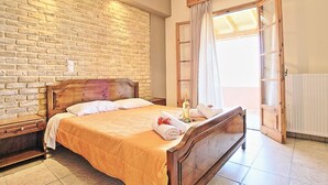A bedroom with a brick wall, wooden bed frame, and a window with curtains. - Amarylis Apartment in Corfu (Corfu)