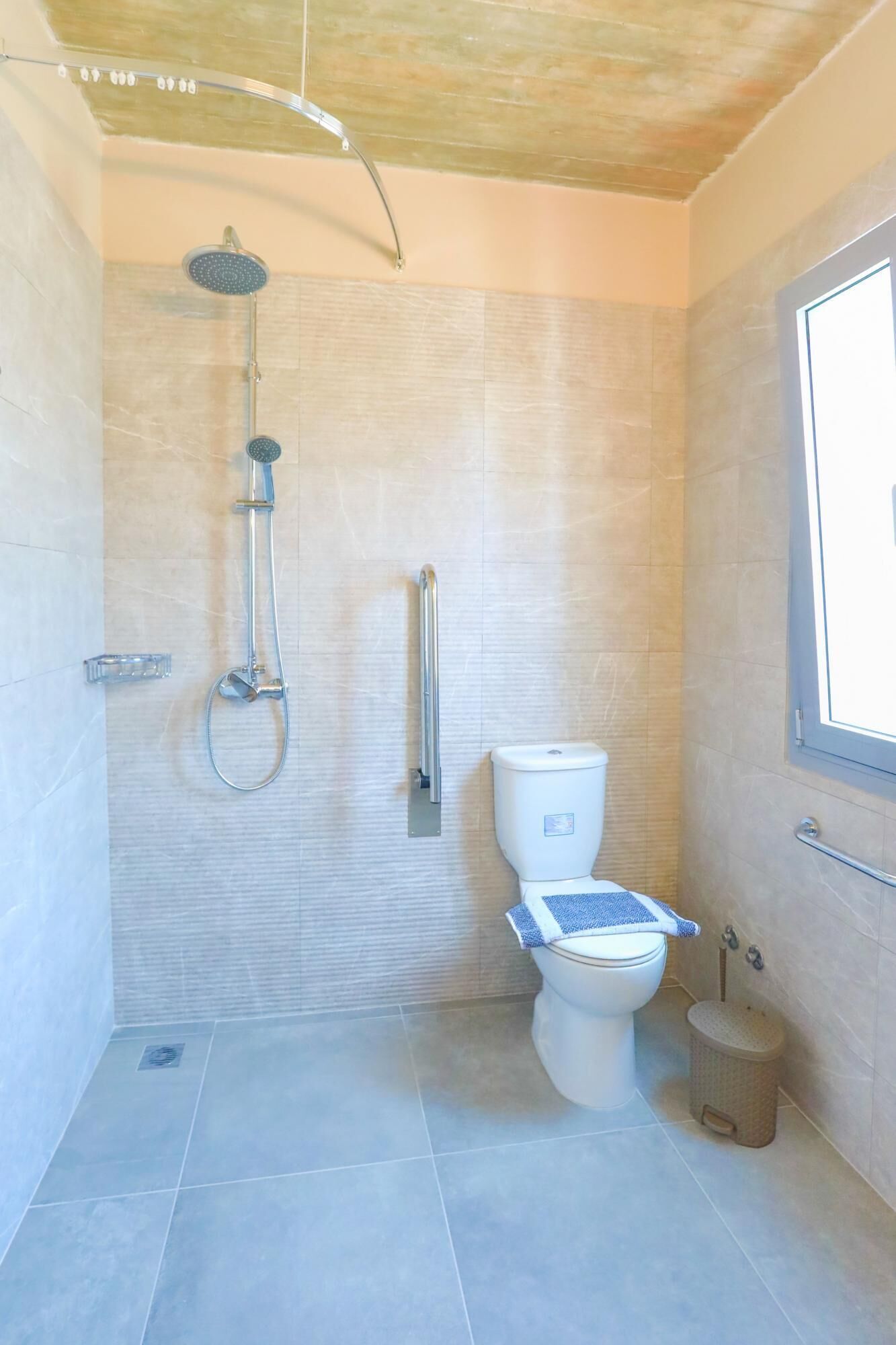 Un baño con ducha, inodoro y ventana.