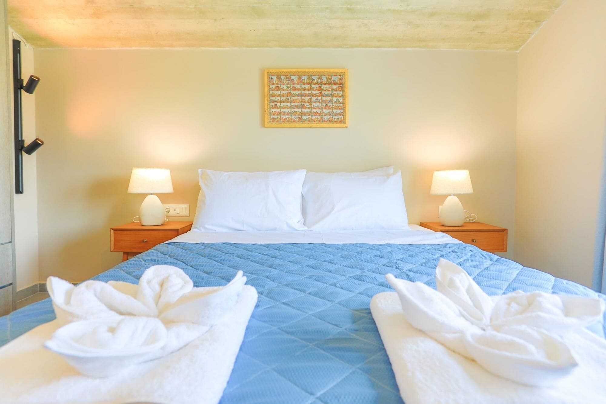 Een hotelkamer met een bed, twee bedlampen, een wandklok en een ingelijste foto.