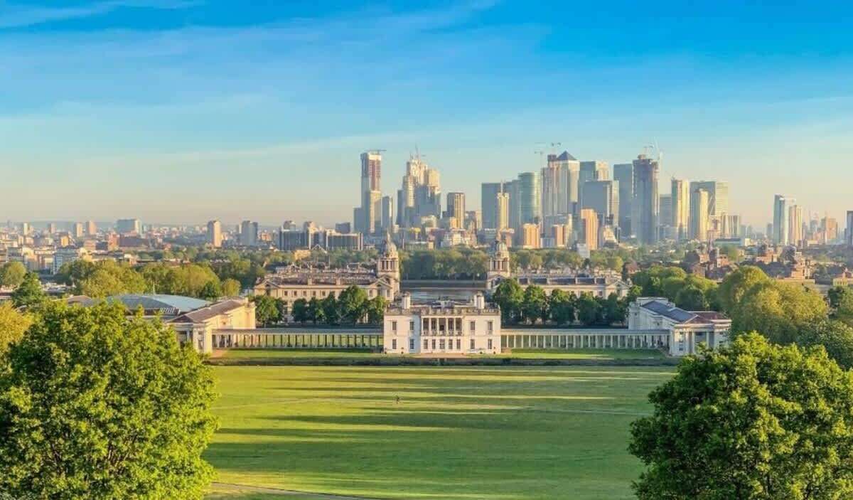 Eine Stadtansicht mit einem markanten historischen Gebäude im Vordergrund und einer Skyline moderner Wolkenkratzer im Hintergrund.