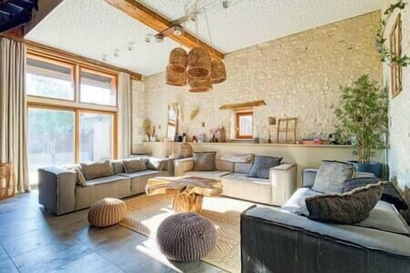 A spacious living room with a large sectional sofa, a coffee table, and a stone accent wall.